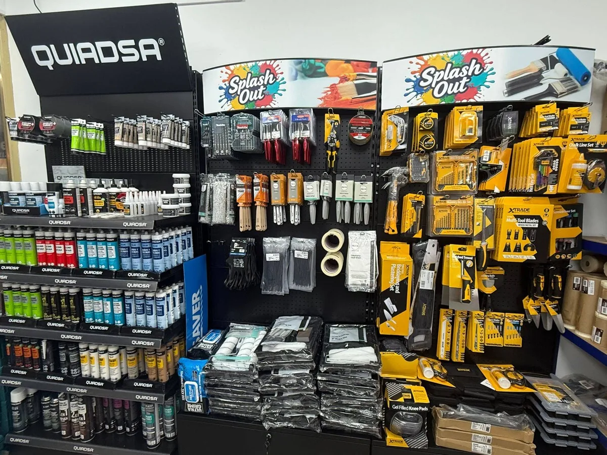 Splash Out shelf headers over the brush and hand-tool wall, next to the Quiadsa stand and a bay of yellow Xtrade tools.